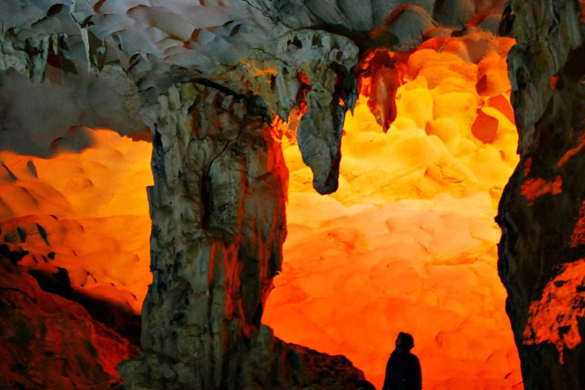 Dau Go Cave Halong Bay bright orange formations Bright orange rock formations and stalactites under warm lighting inside Dau Go Cave Halong Bay.