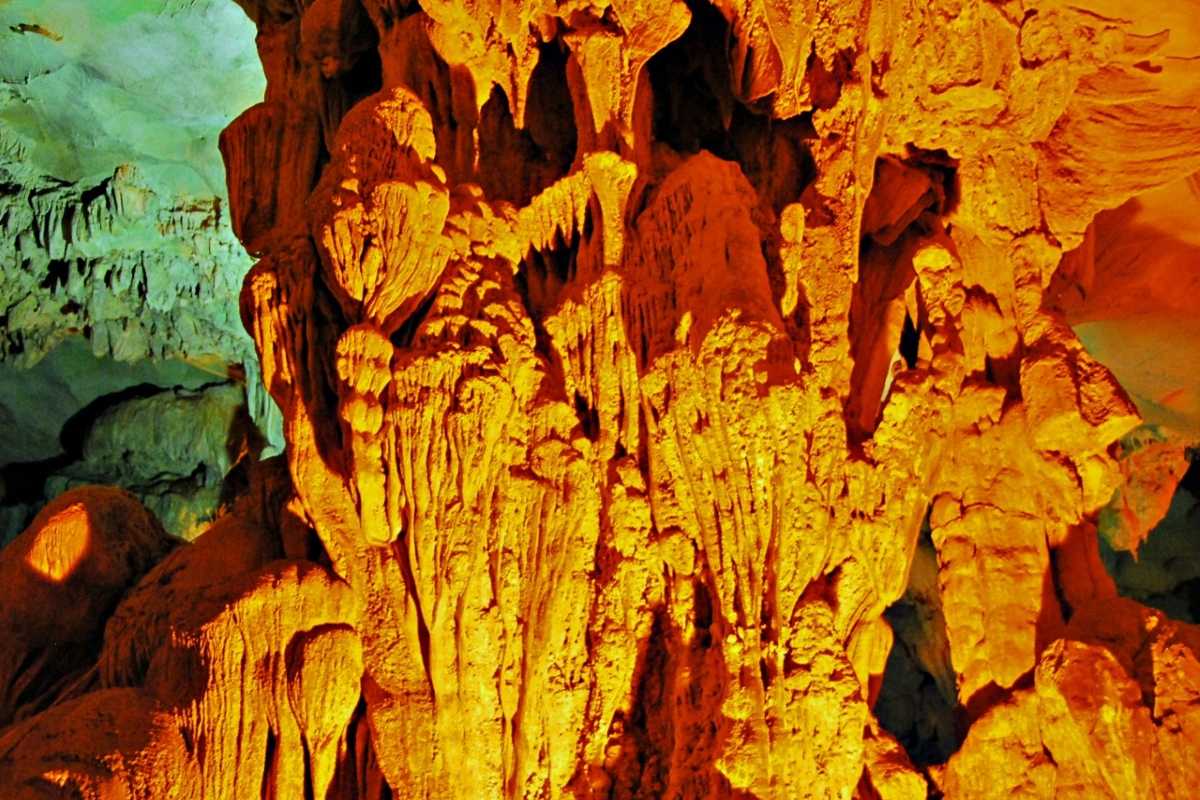 Dau Go Cave Halong Bay orange stalactites close-up Close-up of orange-hued stalactites and rock formations inside Dau Go Cave Halong Bay, richly textured and detailed.