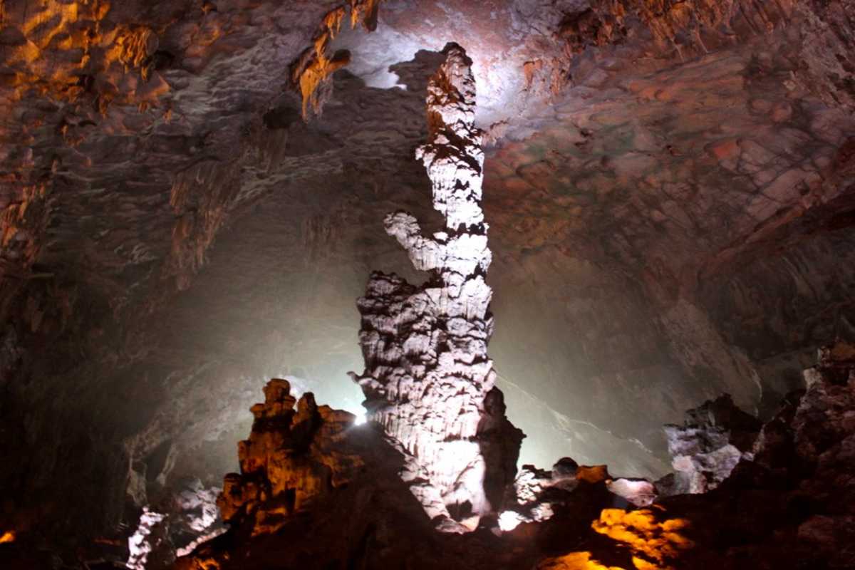 Dau Go Cave Halong Bay tall illuminated stalagmite Tall, illuminated stalagmite formation inside Dau Go Cave Halong Bay with dramatic lighting emphasizing details.