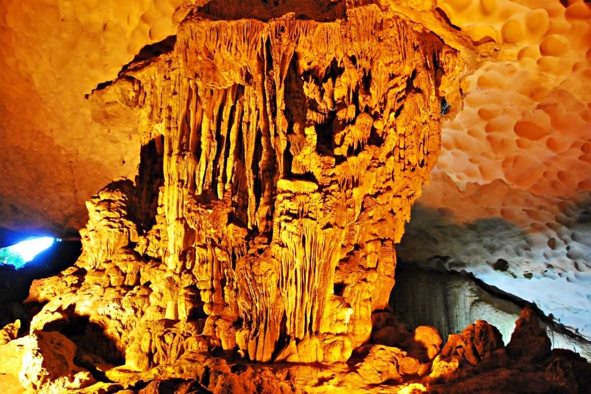 Dau Go Cave Halong Bay towering stalactite formations Tall, impressive stalactite formations illuminated with golden light inside Dau Go Cave Halong Bay.