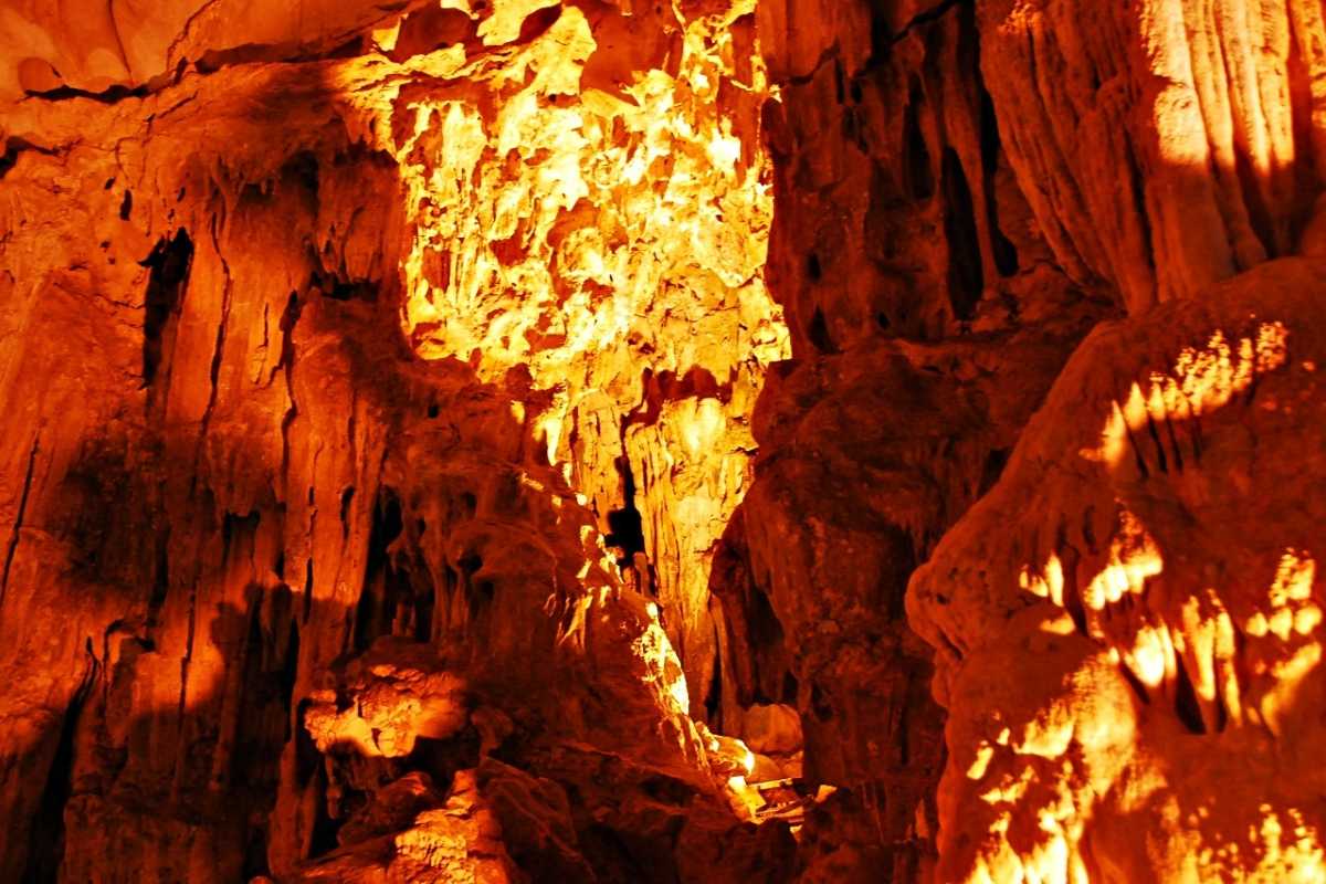 Dau Go Cave Halong Bay visitors admiring cave interior Group of visitors exploring the vast interior of Dau Go Cave Halong Bay with colorful illuminated formations.