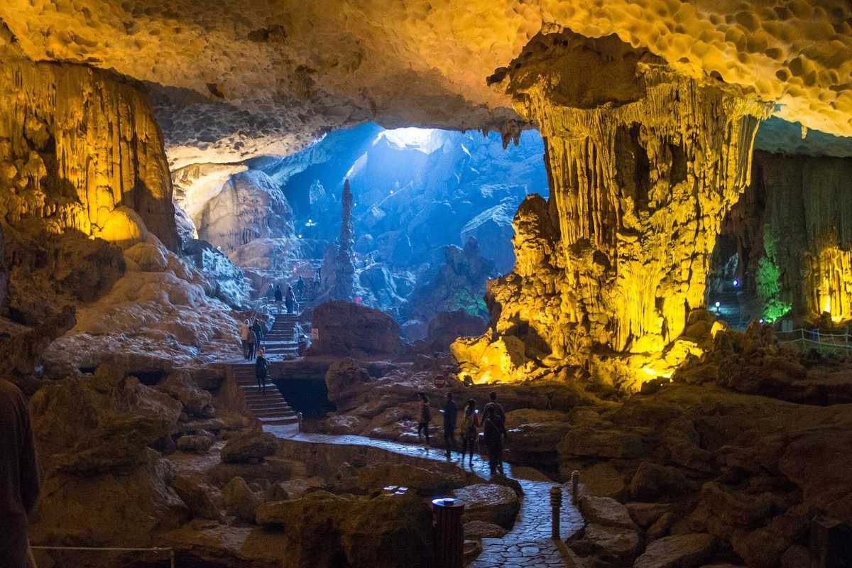Dau Go Cave Halong Bay wide interior view with tourists Wide view of Dau Go Cave Halong Bay’s interior showing visitors walking along pathways under colorful lighting.