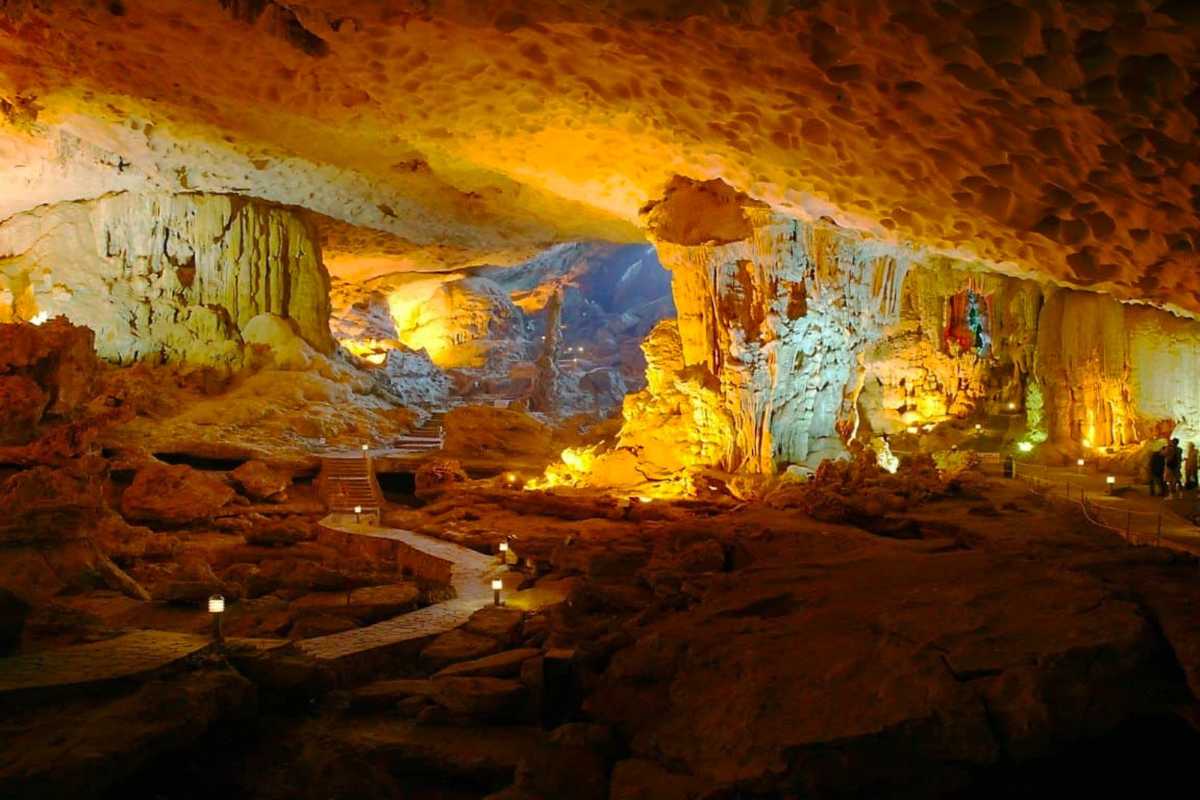 Dau Go Cave Halong Bay wide cave interior with visitors Wide interior shot of Dau Go Cave Halong Bay showing visitors exploring the illuminated rocky formations.