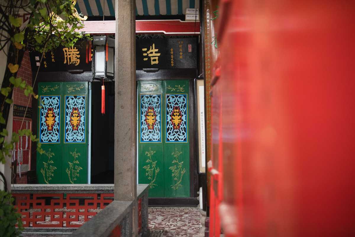 Detailed Wooden Doors in Cantonese Assembly Hall Traditional green wooden doors with intricate carvings at Cantonese Assembly Hall Hoi An