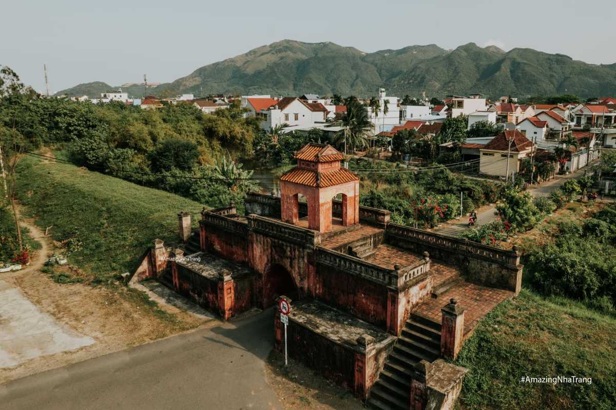 South Gate of Dien Khanh Citadel with old brick architecture surrounded by village scenery and distant hills.