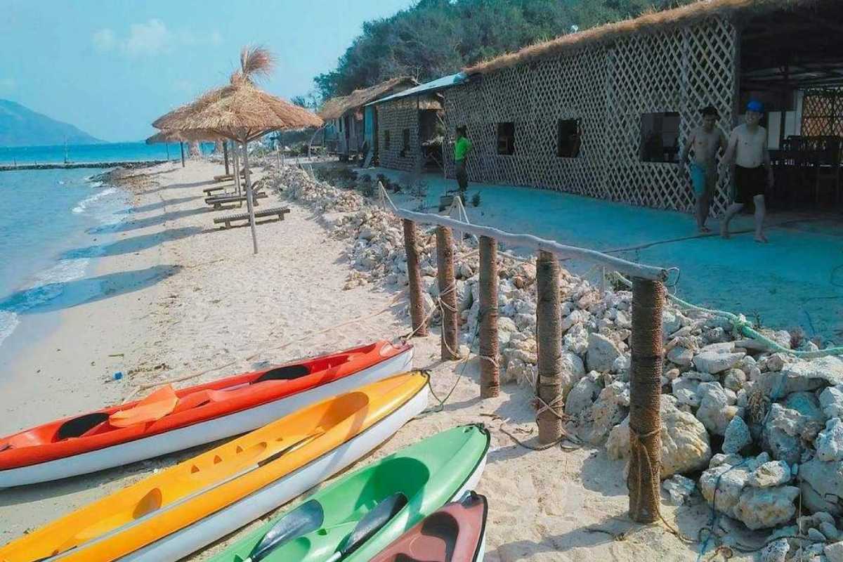 Kayaks lined up on sandy shore at Diep Son Island Nha Trang with calm blue sea and beach umbrellas