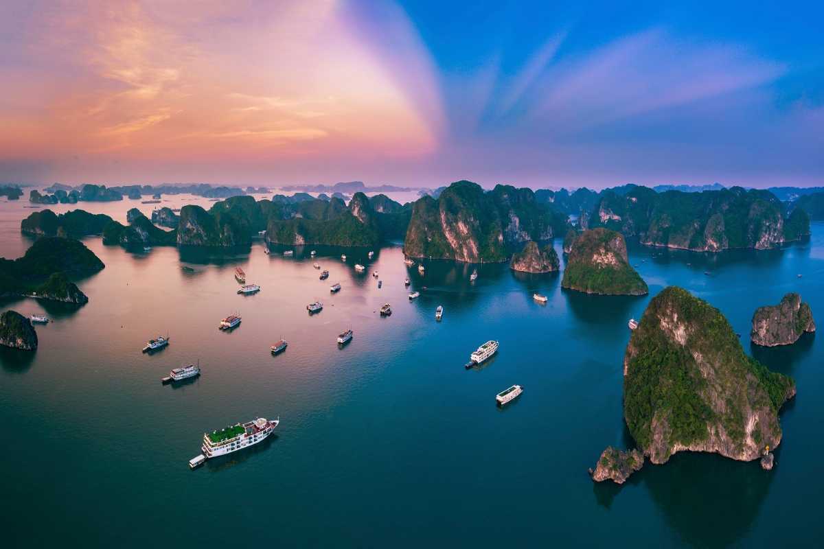 Dinh Huong Islet Halong Bay limestone formation at sunset Limestone formation glowing in the sunset light at Dinh Huong Islet Halong Bay with boats nearby
