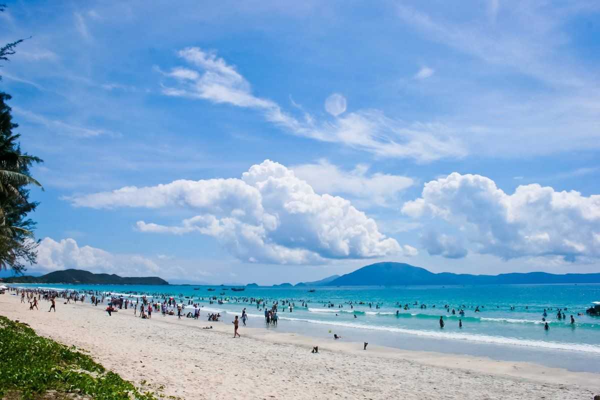 Weekend Crowd at Doc Let Beach Visitors enjoying the sunny waves and blue waters at Doc Let Beach during a busy weekend with scenic mountain views.