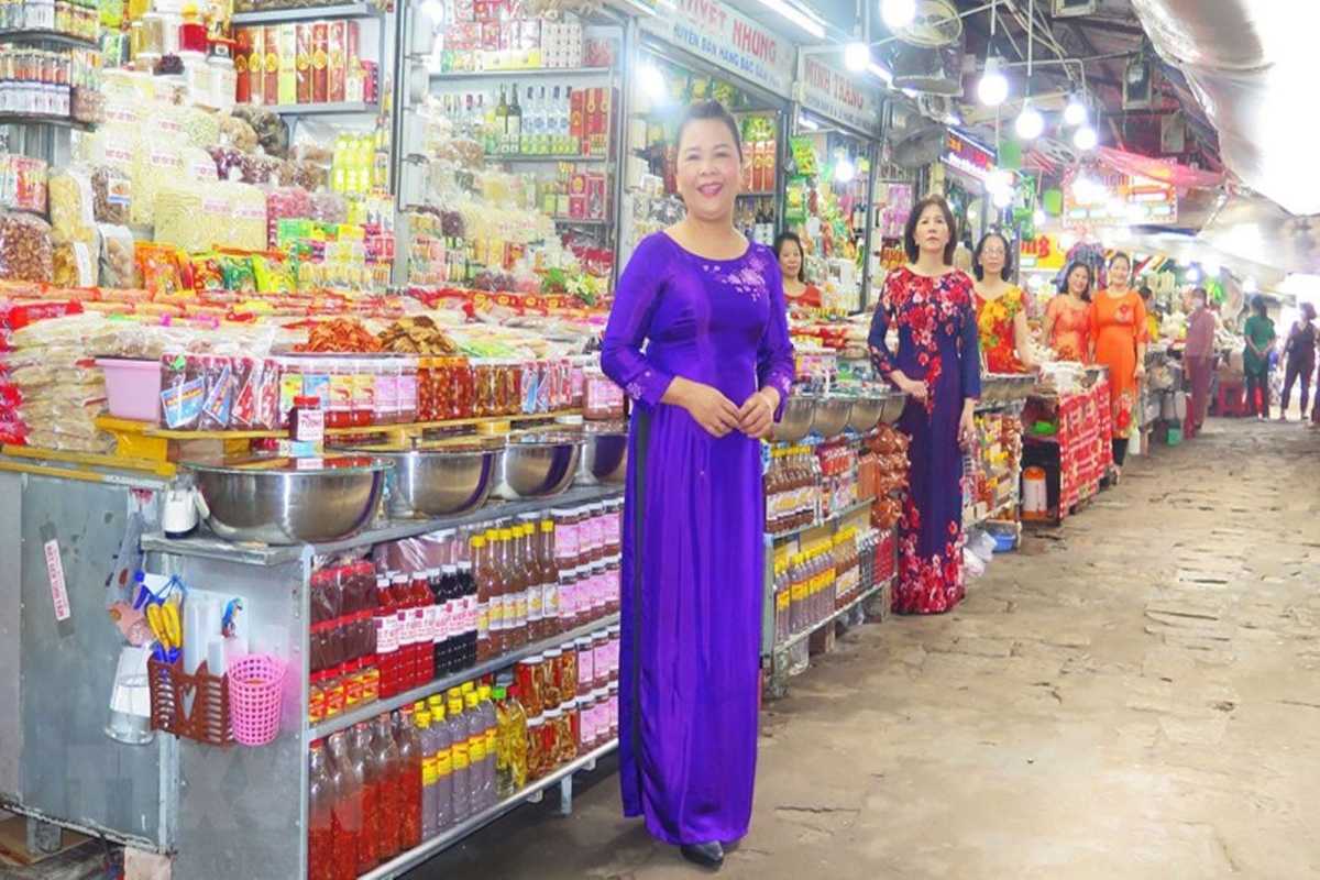 Ao Dai Vendors with Hue Specialties at Dong Ba Market Women in vibrant Ao Dai stand by stalls of Hue specialties, including dried foods and local condiments