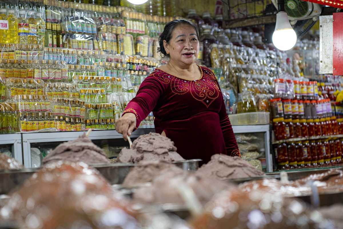 Dong Ba Market Fermented Seafood Vendor in Hue Vendor in Dong Ba Market stands behind mounds of fermented seafood, surrounded by jars and bottles of oil
