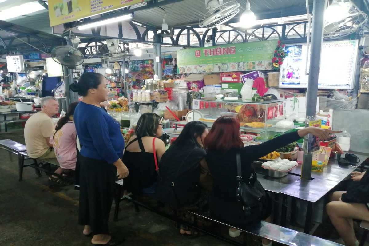 Dong Ba Market Food Court with Local Diners Diners and vendors enjoy meals at Dong Ba Market's indoor food court in Hue, sampling traditional dishes