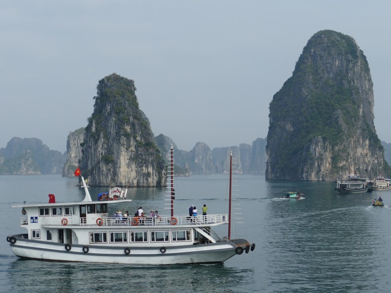 Du thuyền ngắm cảnh tại Vịnh Hạ Long với các núi đá vôi Một chiếc du thuyền đang di chuyển qua Vịnh Hạ Long, với các núi đá vôi và đảo nhỏ dưới bầu trời có mây.