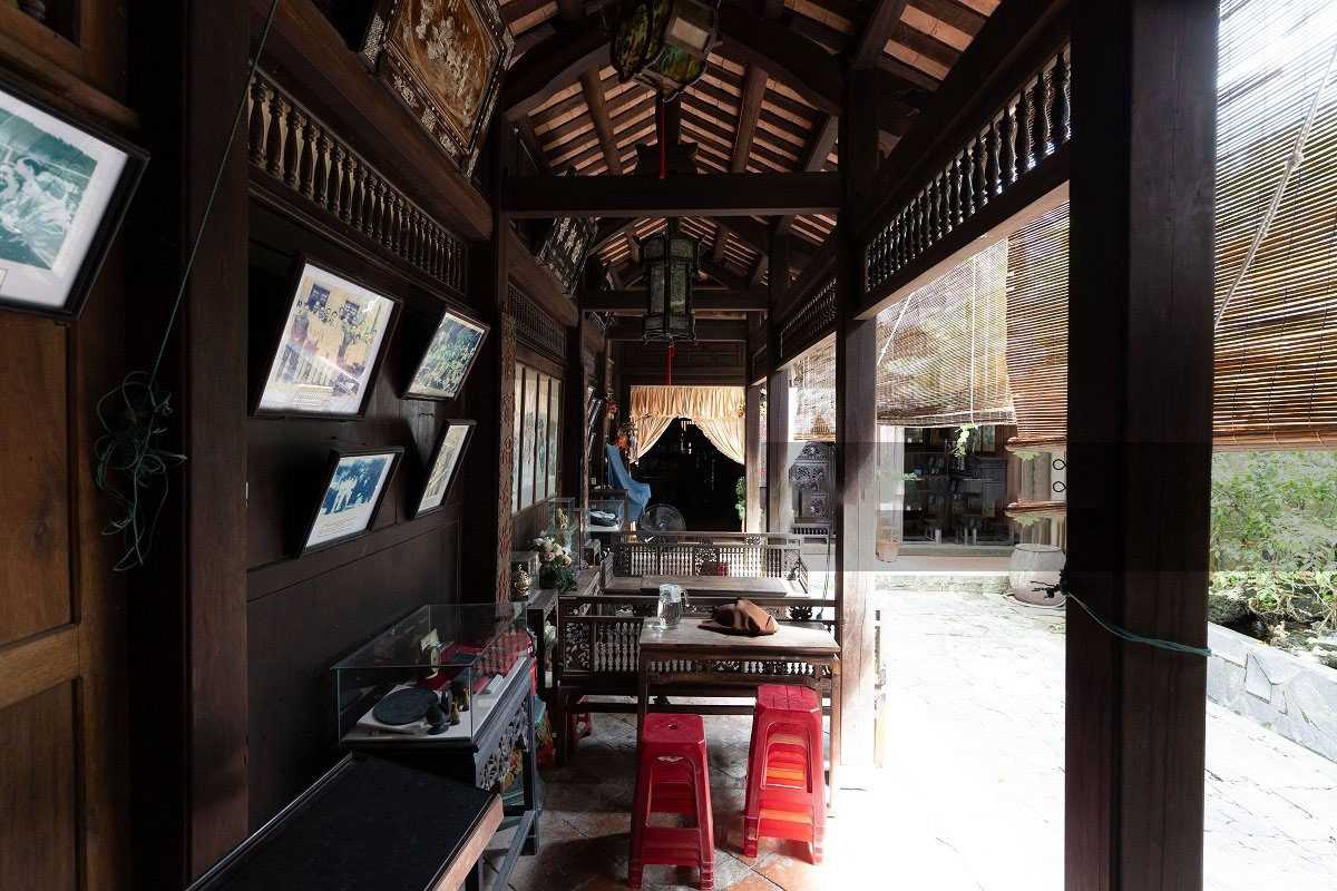 Narrow Corridor with Wooden Furnishings at Duc An Narrow wooden corridor with classic furnishings and framed photos inside Duc An Old House.
