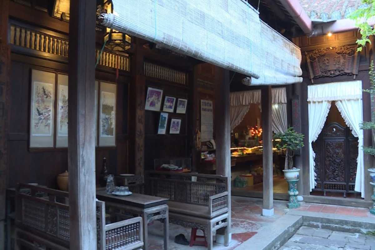 Courtyard Seating at Duc An Old House Hoi An Courtyard area with wooden benches and tables shaded by woven blinds at Duc An Old House.