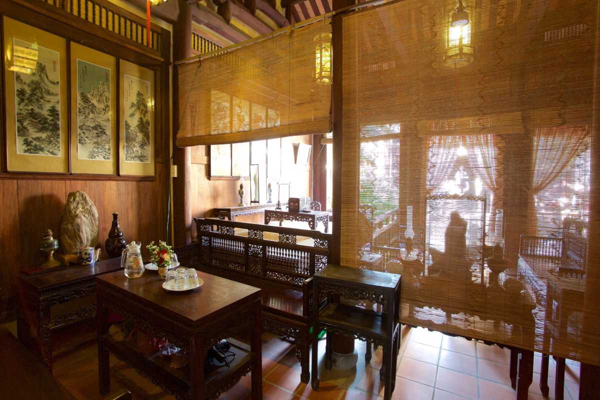 Interior View with Bamboo Curtains at Duc An Old House Interior room of Duc An Old House with bamboo curtains and traditional wooden furniture.