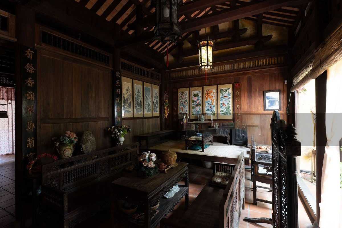 Main Room with Wooden Furniture and Ornate Decor Main room with wooden chairs, tables, and detailed wooden carvings inside Duc An Old House.