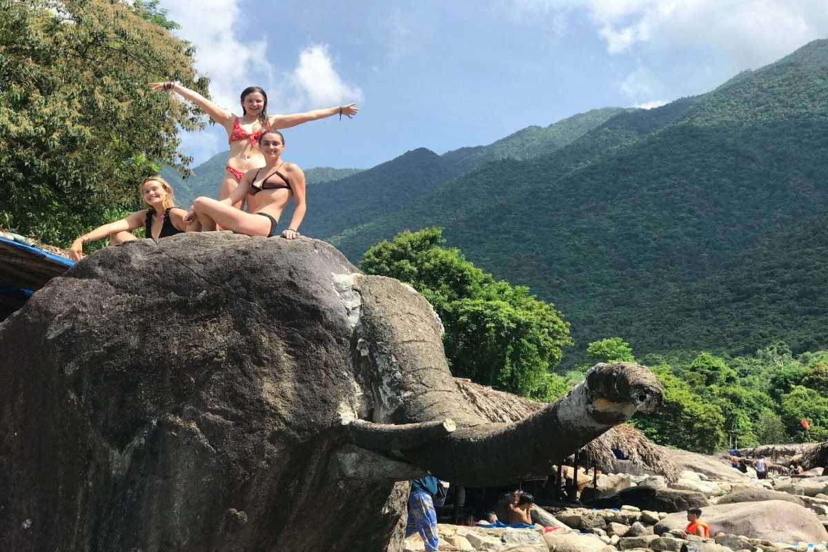 Elephant boulder landmark at Elephant Springs Visitors posing on the famous elephant-shaped rock at Elephant Springs in Hue under a blue sky