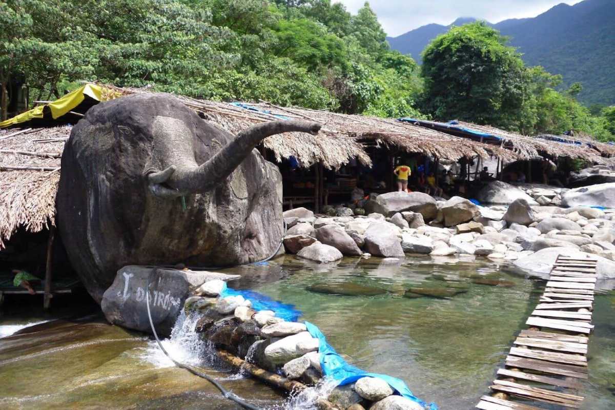Elephant rock landmark with jungle backdrop Close-up of the famous elephant head rock at Elephant Springs in Hue, surrounded by jungle and thatched roofs