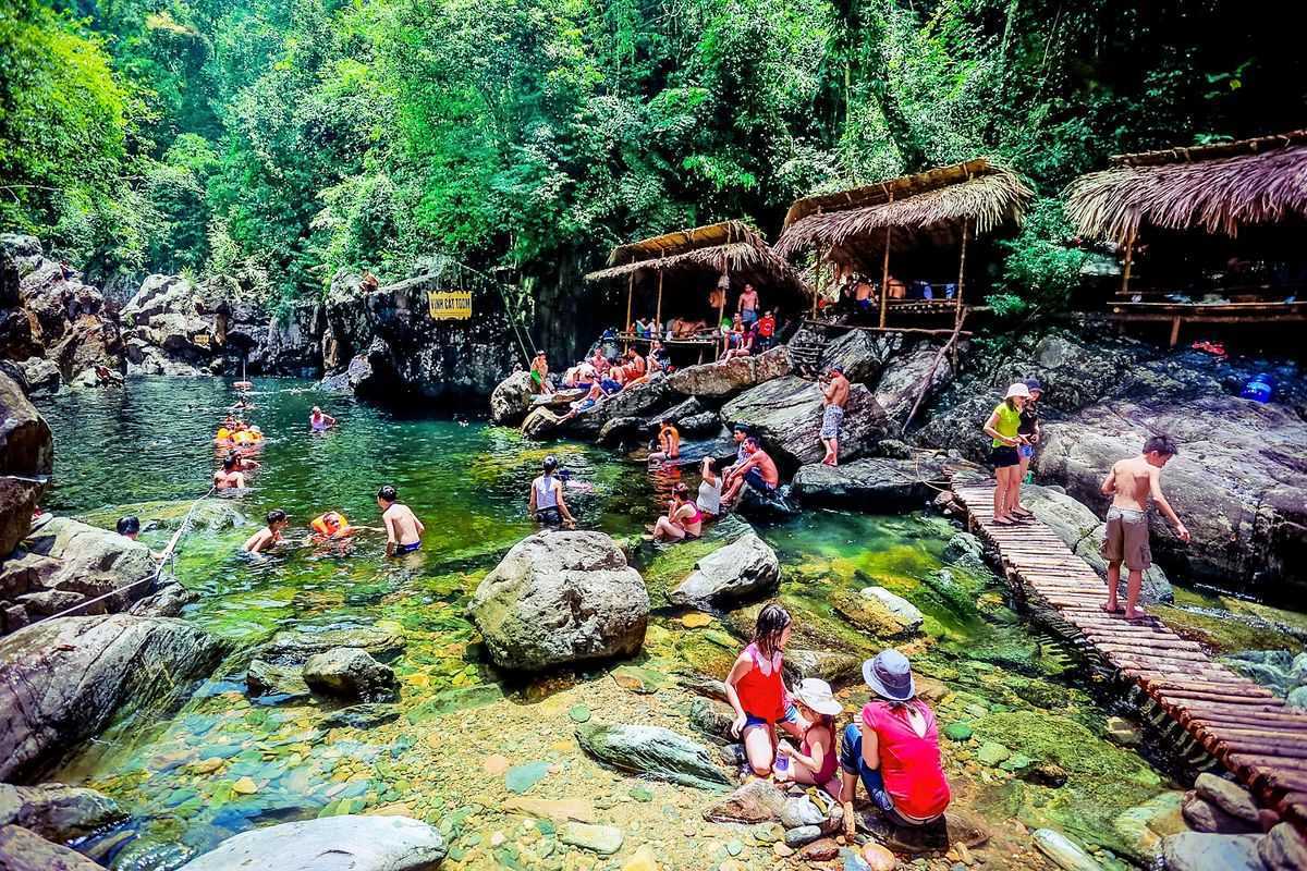 Elephant Springs natural pools and bamboo huts Travelers swimming in natural pools surrounded by rocks and bamboo huts at Elephant Springs in Hue
