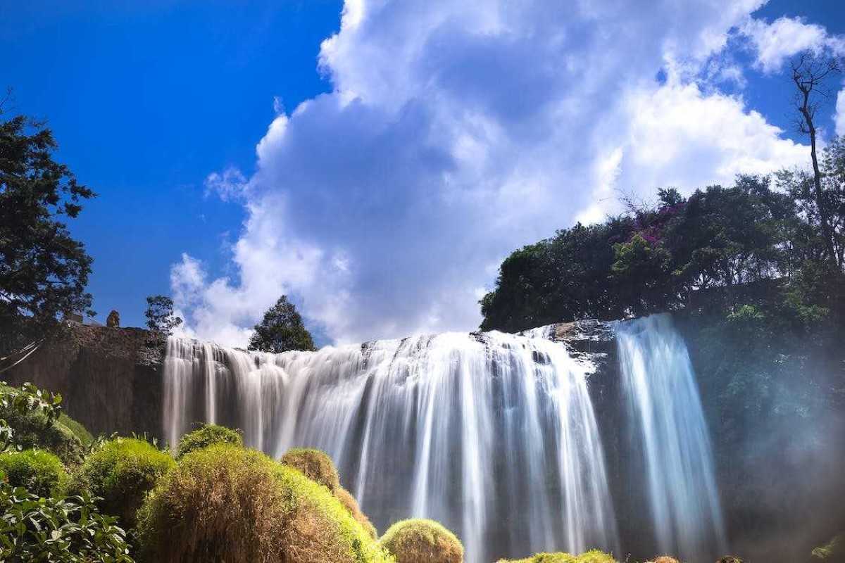 Breathtaking Elephant Waterfall Close-Up Close-up of Elephant Waterfall with cascading water against a vibrant blue sky in Da Lat.