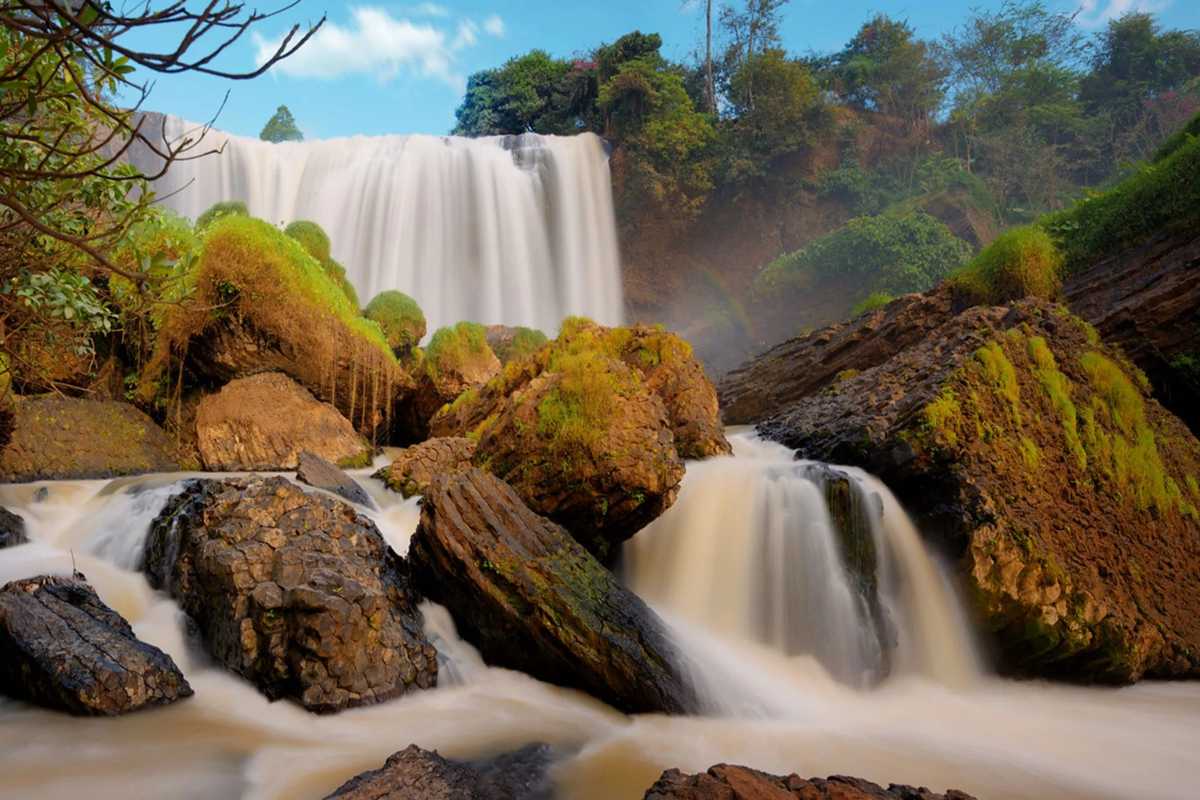 Elephant Waterfall Da Lat golden water cascade Elephant Waterfall Da Lat showing golden-colored water flowing powerfully over jagged rocks under a bright sky