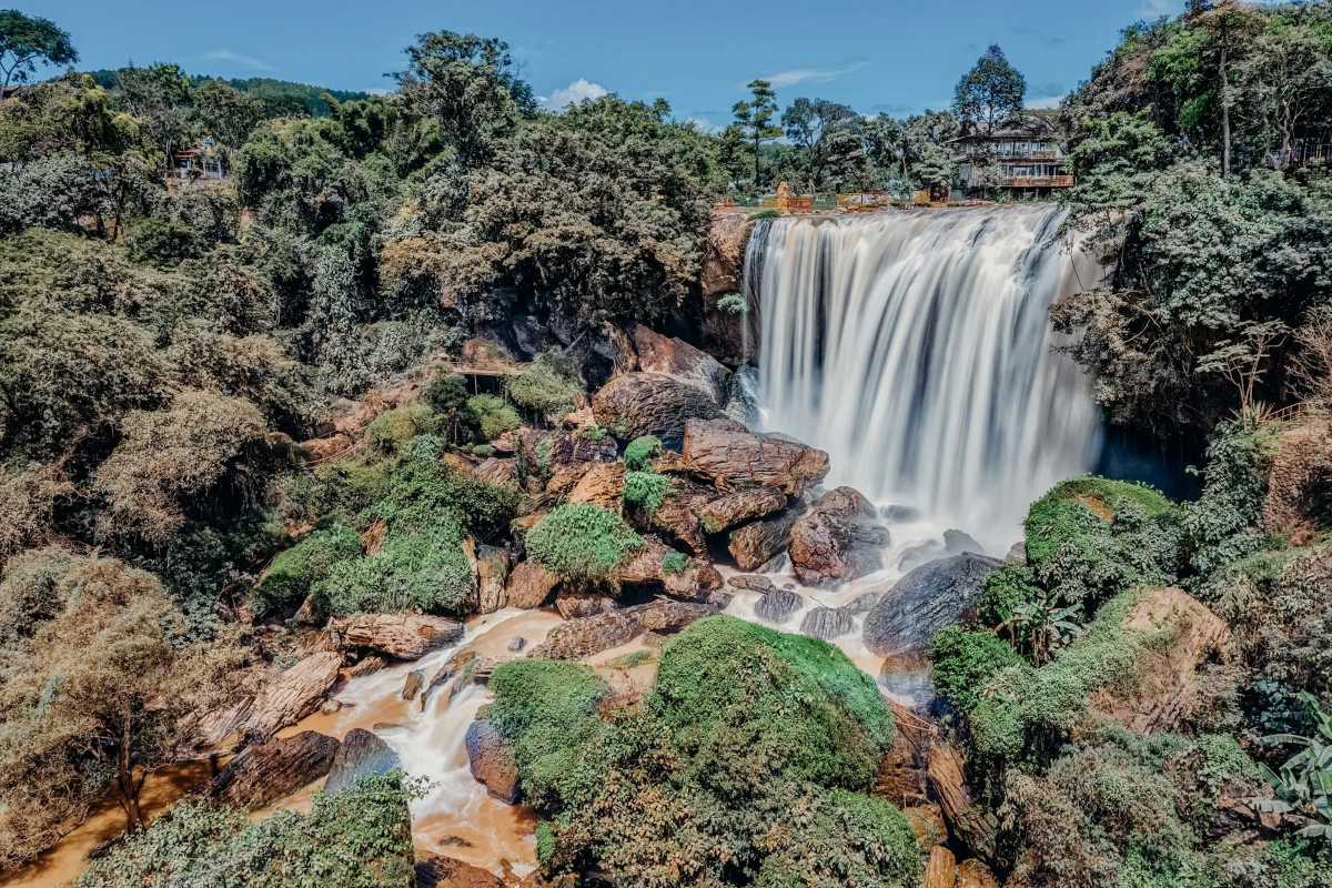Elephant Waterfall Da Lat sunlight over cascade Elephant Waterfall Da Lat with sunlight casting a warm glow over the flowing cascade and surrounding green vegetation