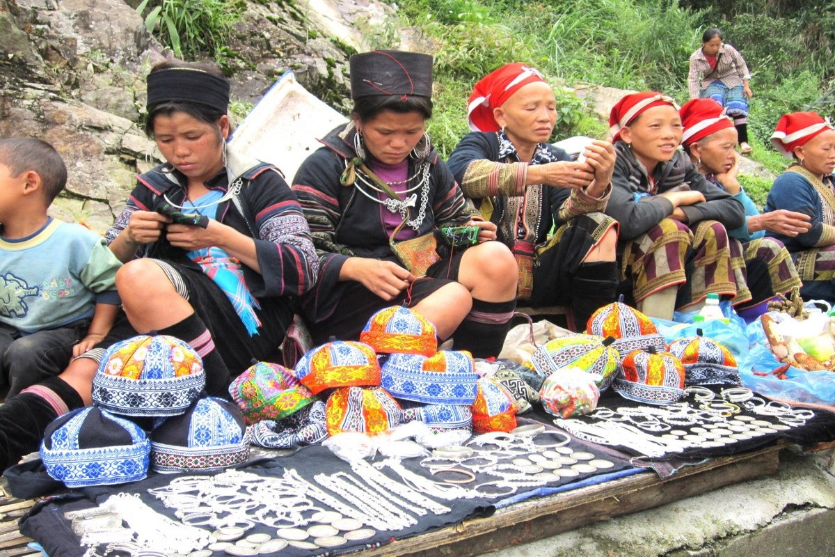 Ethnic vendors in traditional attire selling handcrafted goods at Coc Ly Market, Lao Cai, Vietnam.