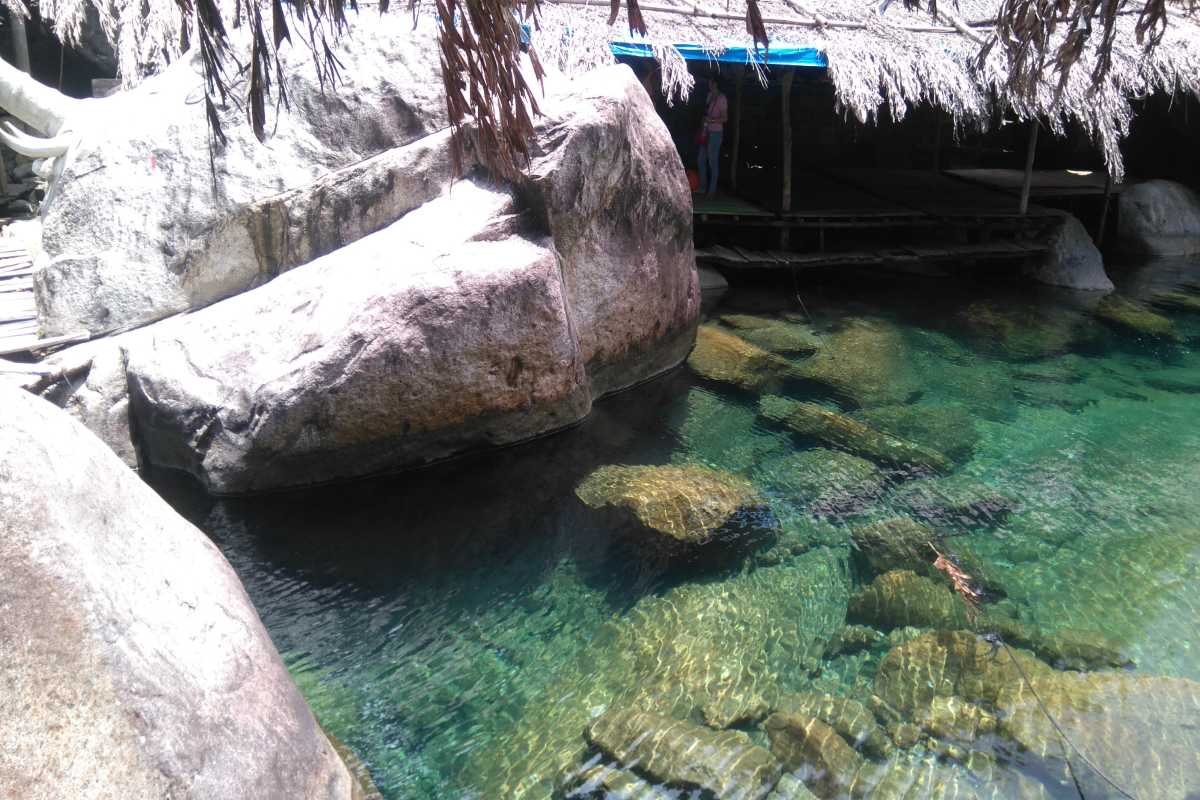 Families swimming in Elephant Springs pools Children and adults swimming in calm spring water pools surrounded by rocks at Elephant Springs Hue