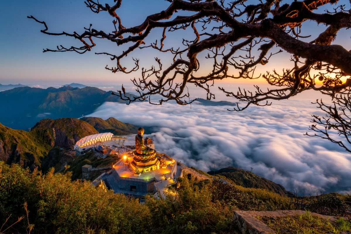Fansipan Mountain Sapa Buddha statue sunrise clouds Fansipan Mountain Sapa illuminated Buddha statue with glowing sunrise and cloud sea framed by mountain silhouettes
