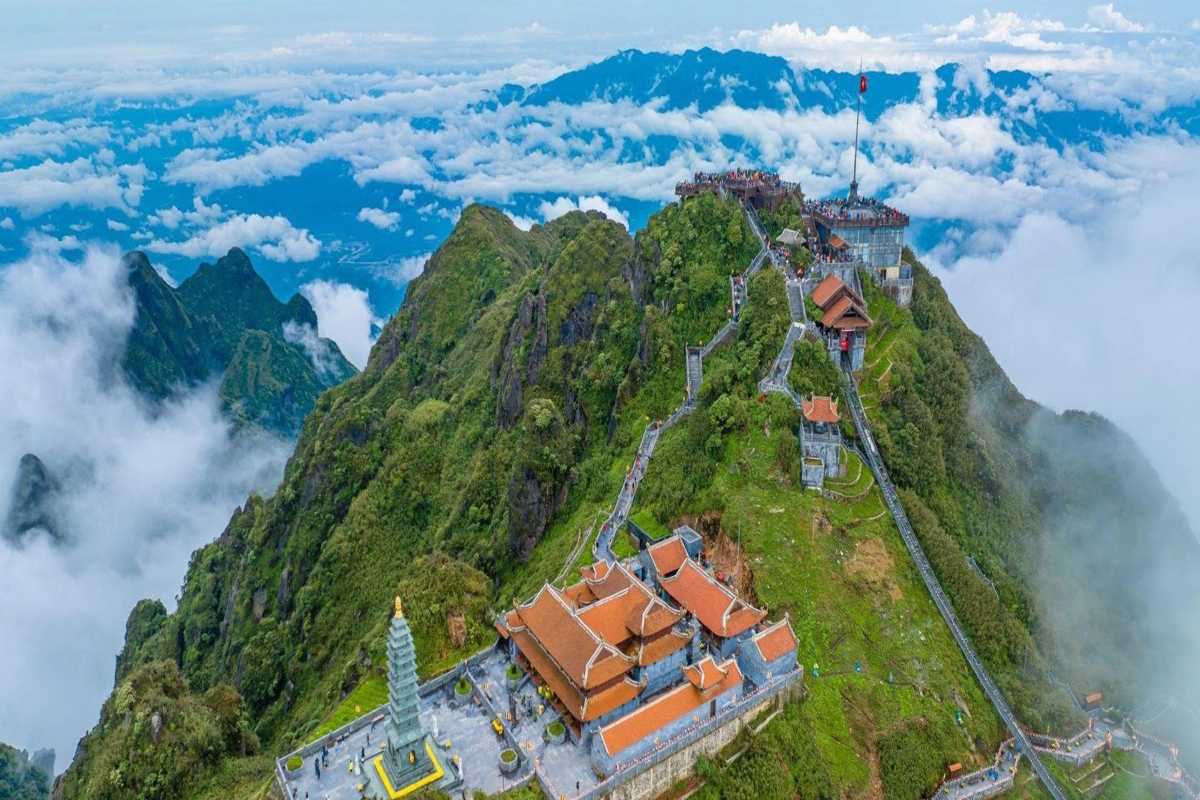 Fansipan Mountain Sapa summit pagoda and flagpole view Fansipan Mountain Sapa pagoda complex and flagpole along ridge with expansive mountain and cloud backdrop