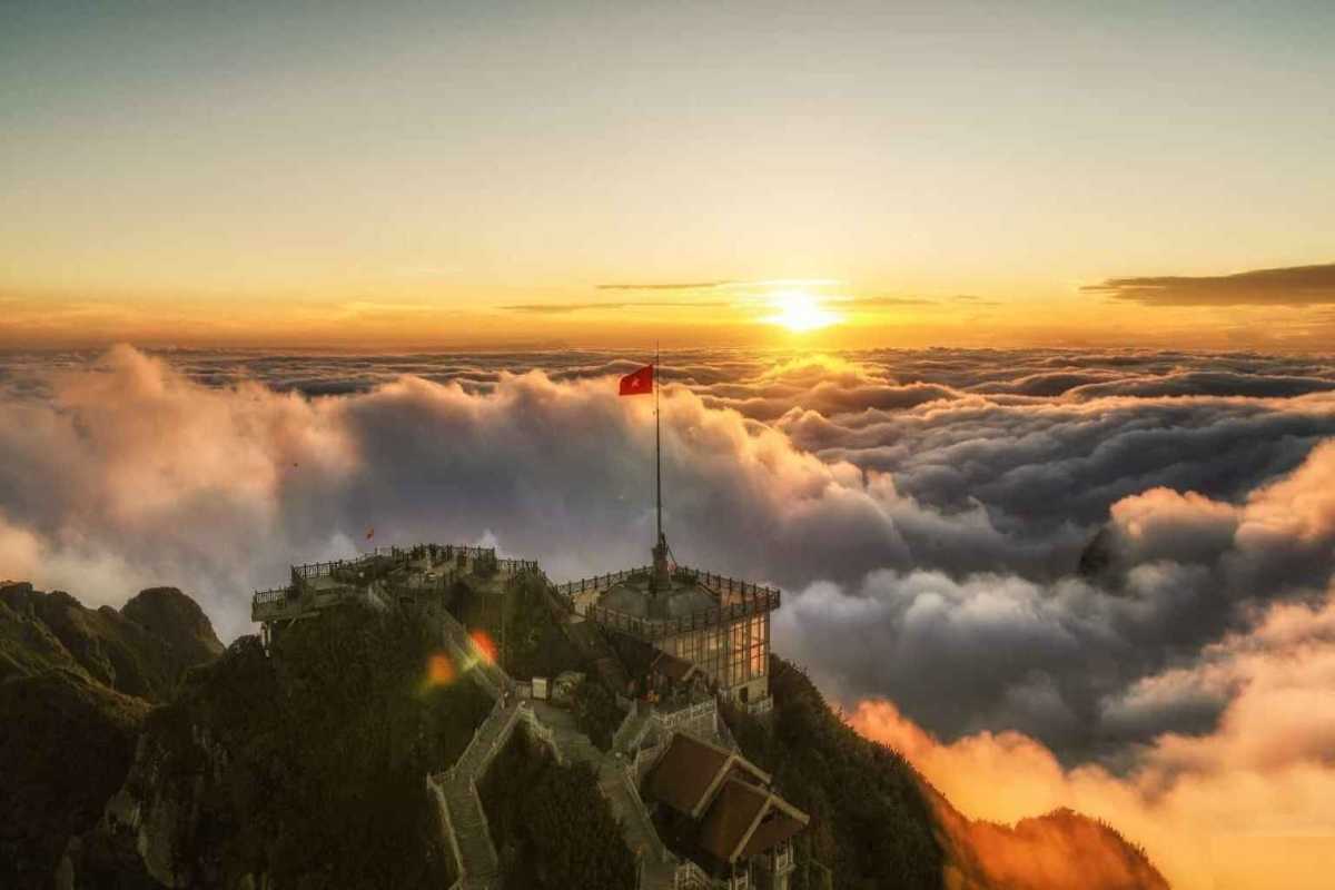 Fansipan Mountain Sapa sunrise at summit flagpole Sunrise at Fansipan Mountain Sapa summit with Vietnamese flag and panoramic cloudscape above Indochina’s highest peak