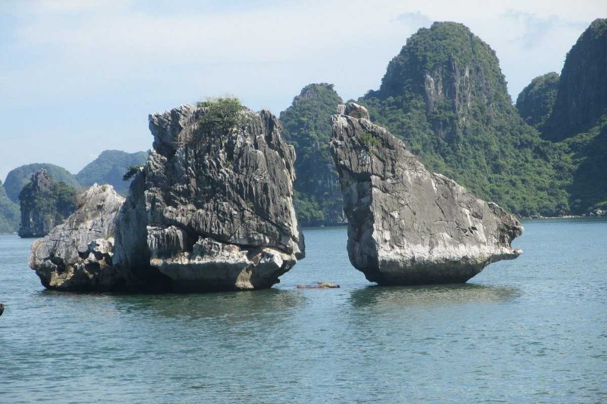 Fighting Cocks Islet Halong Bay Clear Day with Bright Blue Sky Clear day view of Fighting Cocks Islet Halong Bay with bright blue sky and emerald waters, surrounded by other islets.