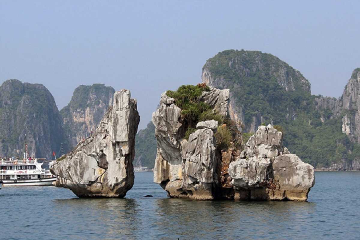 Fighting Cocks Islet Halong Bay rock formations and boats Limestone rock formations of Fighting Cocks Islet Halong Bay surrounded by tourist boats