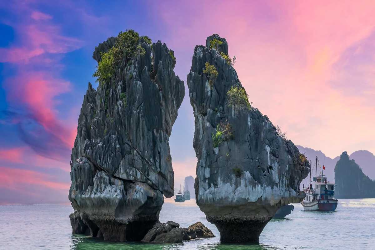 Fighting Cocks Islet Halong Bay at Sunset with Colorful Sky Fighting Cocks Islet Halong Bay bathed in warm sunset light under a colorful sky with surrounding limestone islands.