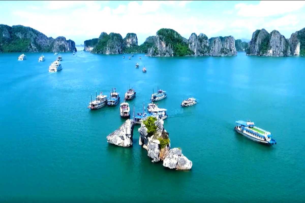 Fighting Cocks Islet Halong Bay tourists on sightseeing boat Sightseeing boat with tourists near Fighting Cocks Islet Halong Bay limestone formations