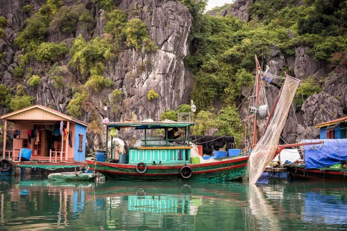 Fishing Boat and Floating Home in Ba Hang A traditional green-and-red fishing boat anchored next to a floating home in Ba Hang Fishing Village.