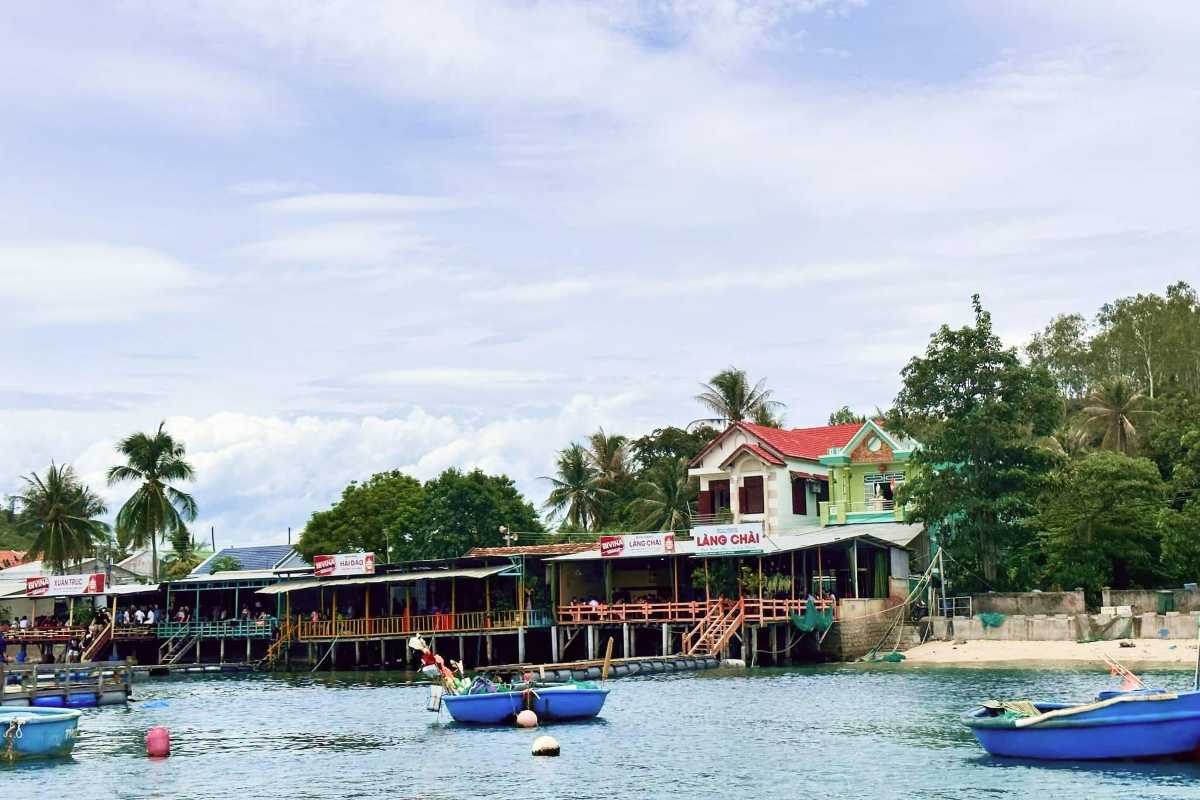 Stilt Seafood Restaurants near Mot Island Floating seafood restaurants on stilts along the shoreline of Mot Island with palm trees and anchored boats.