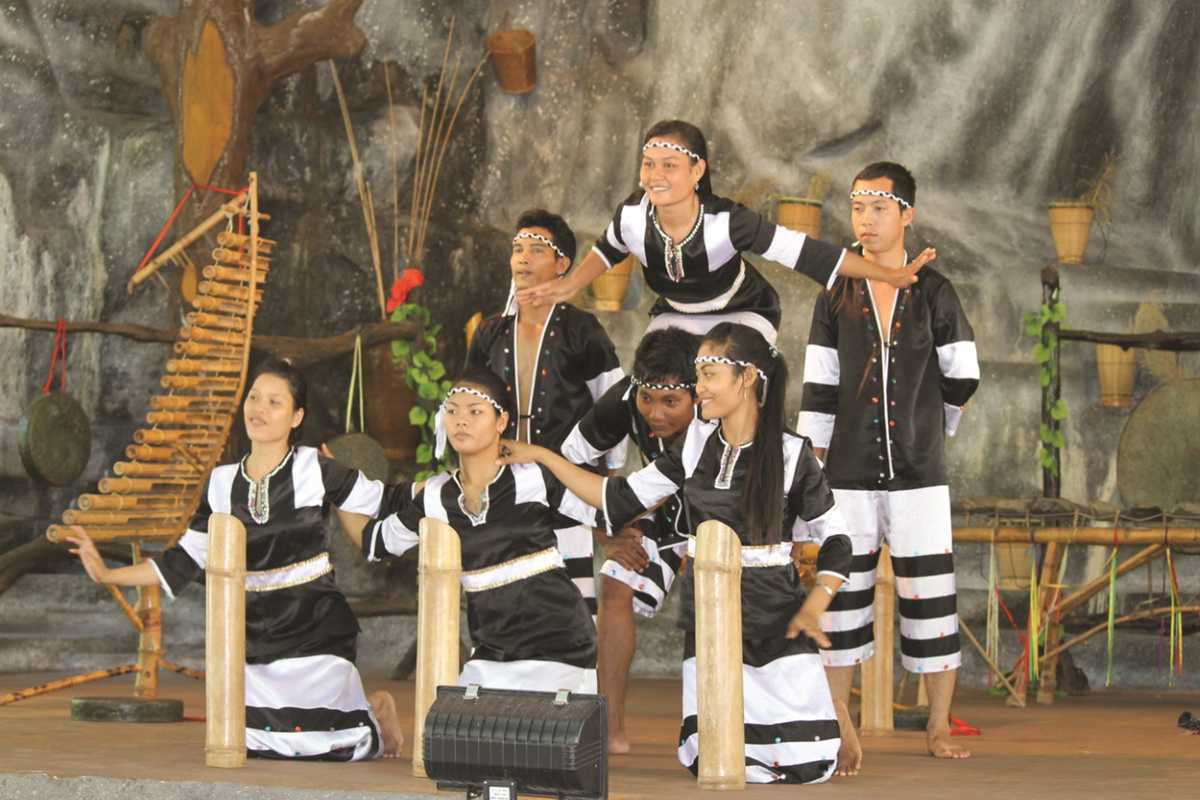 Traditional folk music near Cai River Group of villagers in black attire perform traditional folk music indoors using bamboo instruments near Cai River.