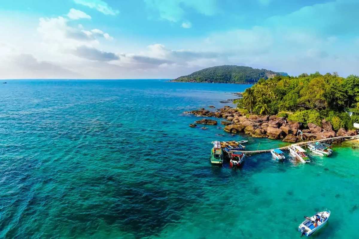 Gam Ghi Island Pier and Boats Pier with boats docked at Gam Ghi Island Phu Quoc surrounded by clear turquoise waters and green landscape.