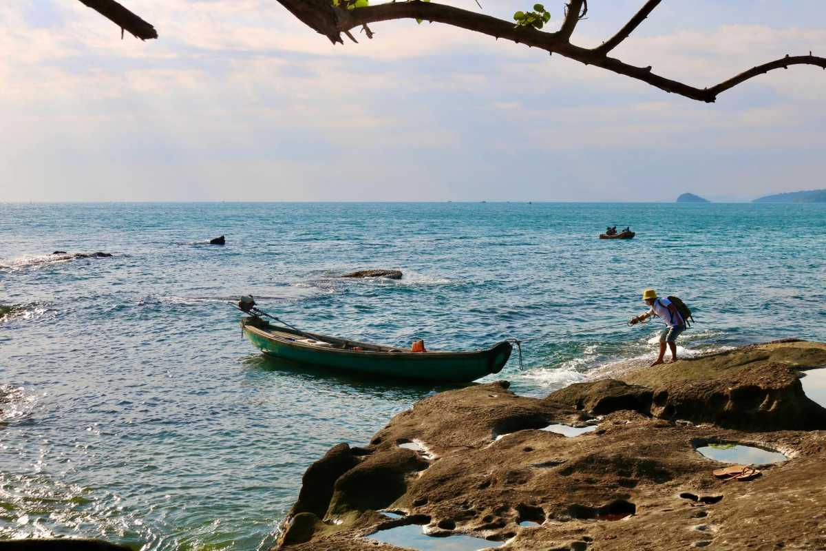A scenic view of Ganh Dau Cape with a local fisherman casting a net in the shallow waters.