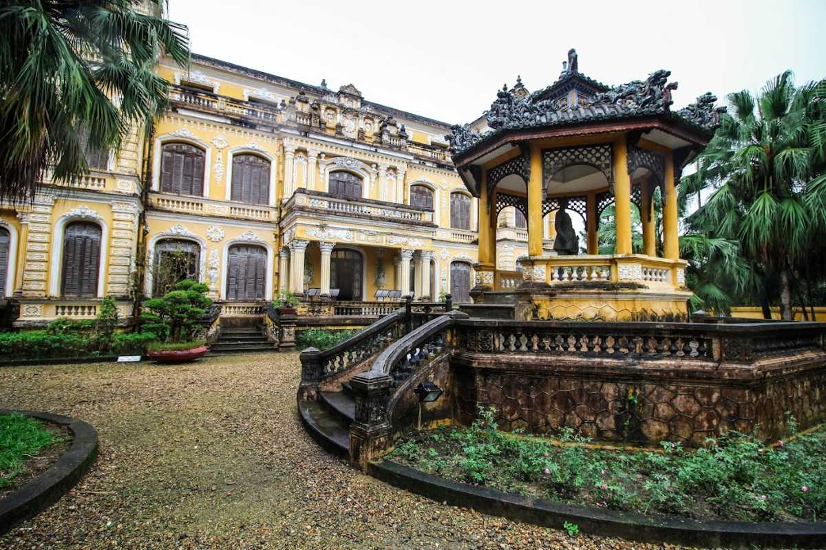 Garden and Pavilion of An Dinh Palace in Hue Garden area with traditional pavilion and yellow colonial-style building at An Dinh Palace