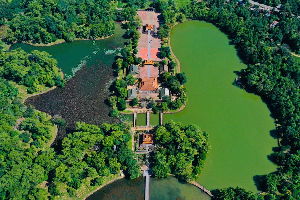 Gia Long Tomb Central Axis and Twin Lotus Lakes Aerial view of Gia Long Tomb's central axis flanked by two lotus lakes and lush forest in Hue, Vietnam.
