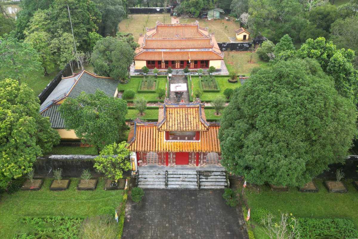 Main Gate and Gardens of Gia Long Tomb Complex Aerial perspective of Gia Long Tomb's ornate gate, orange tiled roofs, gardens, and lush green trees in Hue, Vietnam.
