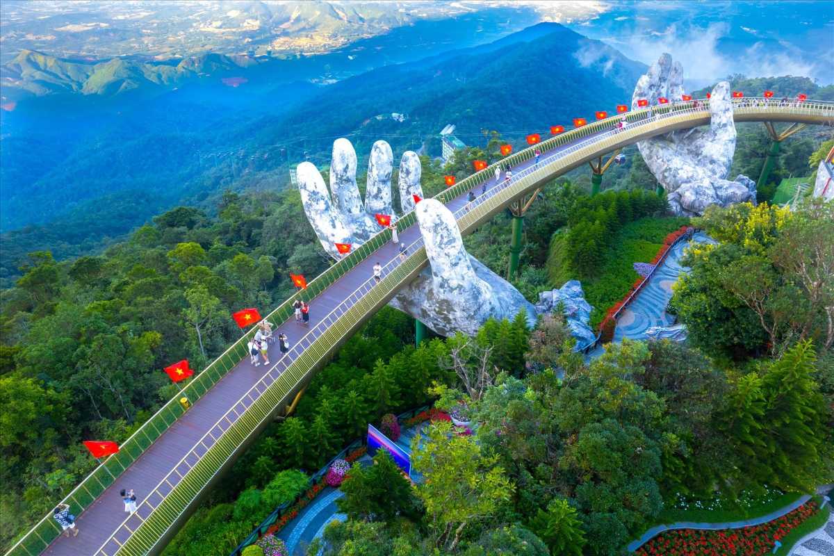 Golden Bridge Da Nang aerial view Vietnamese flags Ba Na Hills Aerial view of Golden Bridge Da Nang lined with Vietnamese flags, giant hands, green Ba Na Hills