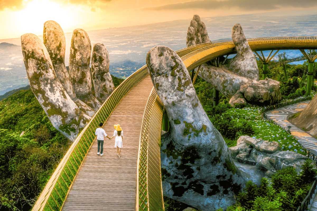 Golden Bridge Da Nang couple romantic walk sunrise Couple holding hands walking across Golden Bridge Da Nang, giant stone hands, sunrise in background