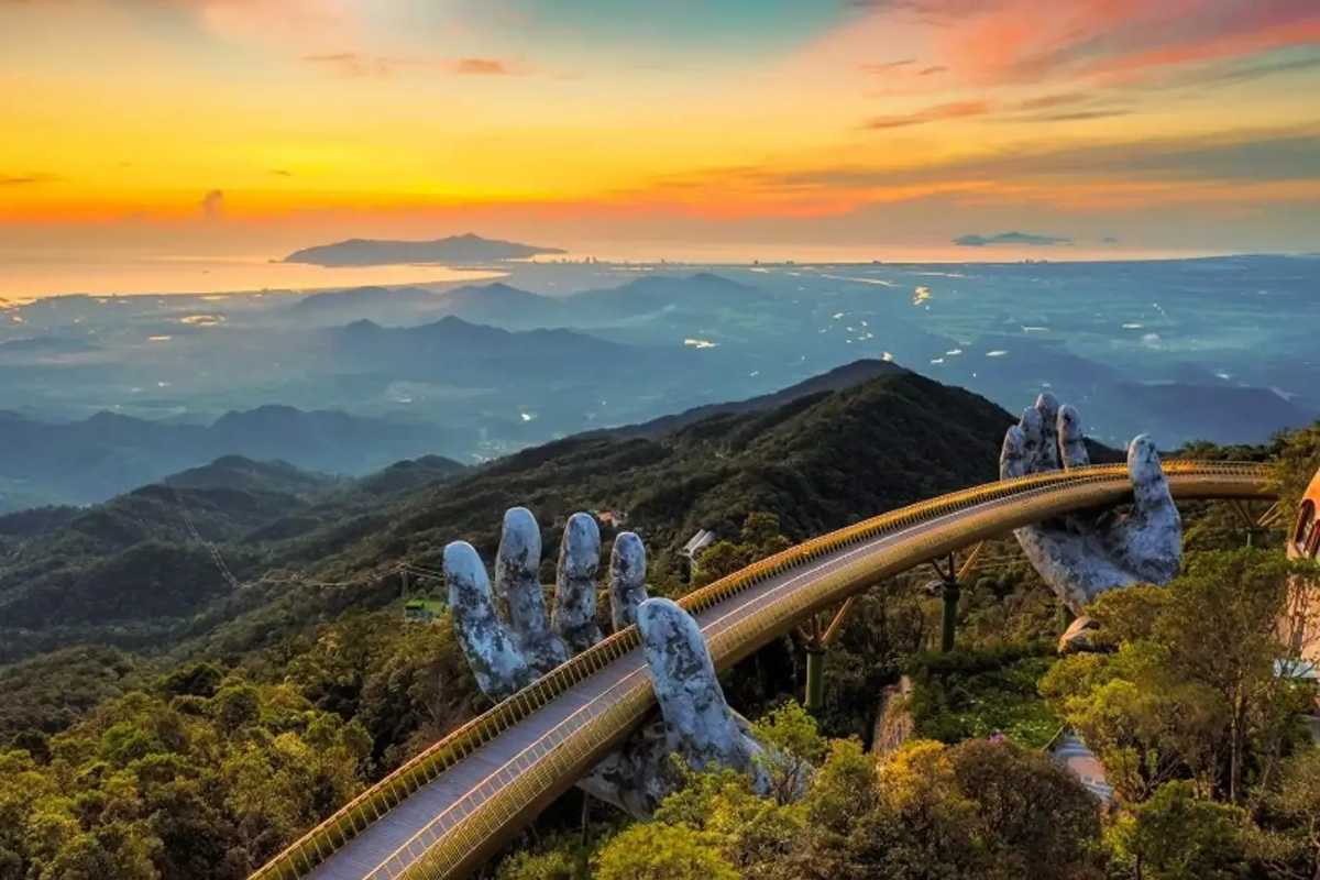 Golden Bridge Da Nang panoramic sunset view Ba Na Hills Golden Bridge Da Nang at sunset, giant hands holding bridge above Ba Na Hills, golden sky, coastline