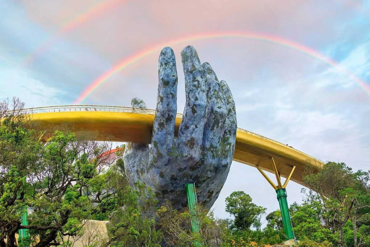 Golden Bridge Da Nang rainbow giant hand closeup Ba Na Hills Closeup of Golden Bridge Da Nang giant hand holding gold walkway, rainbow above, trees below