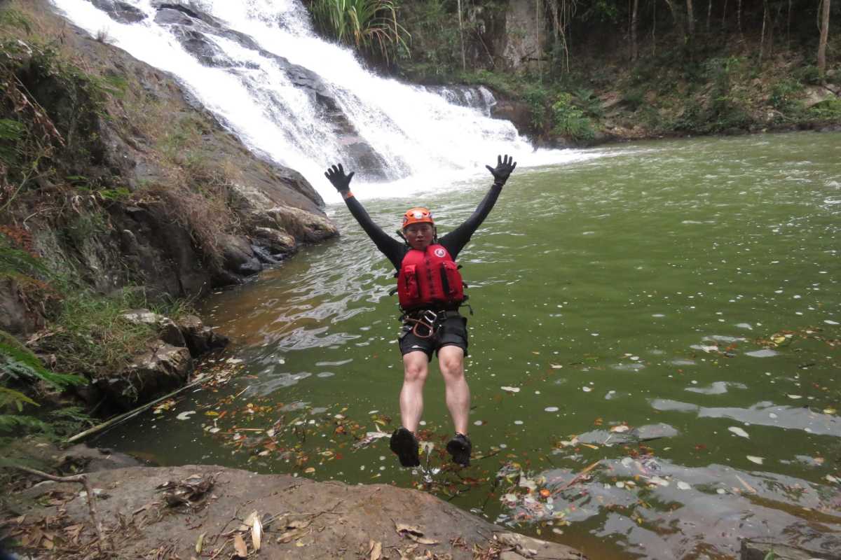 Group Canyoning Activity at Datanla Waterfalls Group of people gearing up for canyoning by the waterfall at Datanla Waterfalls, wearing helmets and gear