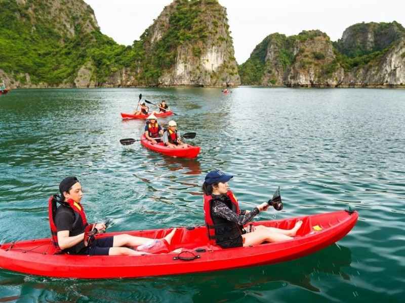 A group kayaking through the scenic limestone karsts of Cong Do Area