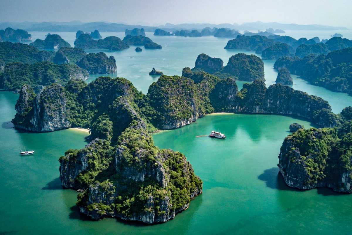 Ha Long Bay Lush Limestone Islands and Boats Lush limestone islands dotted with cruise boats on the emerald waters of Ha Long Bay under a clear blue sky.